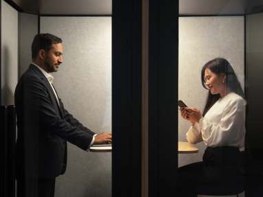 Man working at his laptop and woman looking at her phone in back to back Orangebox Be my guest pods