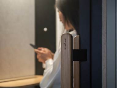Woman sitting and looking through her phone inside a Orangebox Be my guest® pod